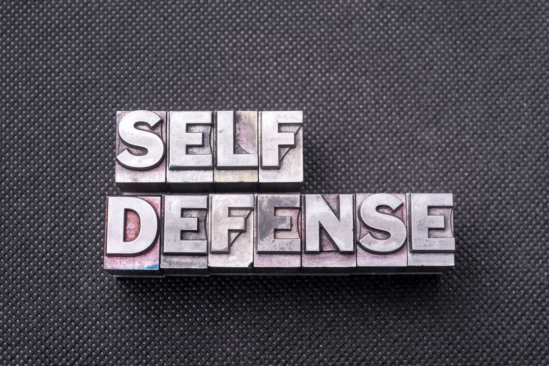 self defense phrase made from metallic letterpress blocks on black perforated surface